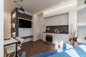 A modern kitchen with white cabinets, a built-in oven, and a dining area with a table and chairs. - GuestHost - Monteverde Classy Apartment (Roma)