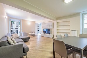 A modern living room with a sofa, a dining table, and a TV.