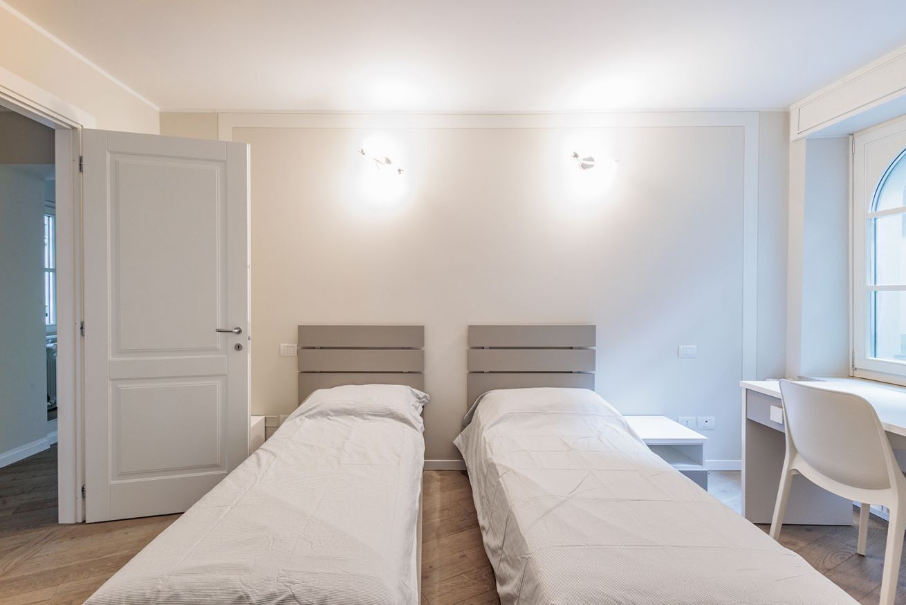 A bedroom with two beds, a desk, and a chair.