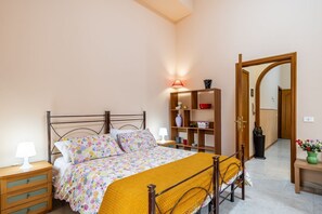 Une chambre à coucher comprenant un lit, des tables de chevet, une lampe, une étagère avec des objets décoratifs et un miroir.
