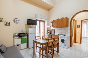 Un espace de vie compact comprenant un coin repas, une kitchenette et un espace dédié à la buanderie.