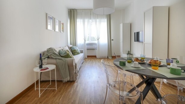 Ein modernes Zimmer mit einer Couch, einem Esstisch und einem Fernseher.