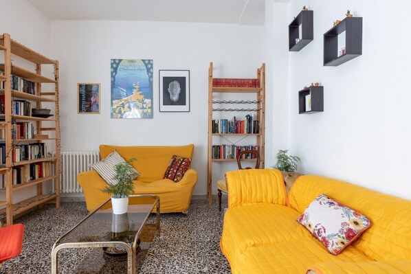 A living room with a yellow sofa, a coffee table, and two bookshelves filled with books.