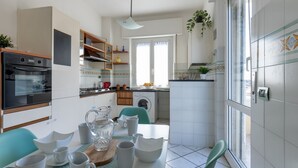 A modern kitchen with a dining area, built-in oven, and a view of the outside. - GuestHost - Porta a Lucca - Pisa Bright Apartment with Balcony (Pisa)
