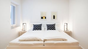A neatly made double bed with two pillows, a bedside table with a lamp, and two framed artworks on the wall. - Modernes Apartment mit Terrasse am Klopeiner See (Unterburg am Klopeiner See)