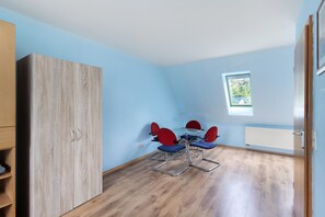 Une pièce avec une armoire en bois, une table à manger entourée de chaises rouges et une fenêtre donnant sur un paysage verdoyant.