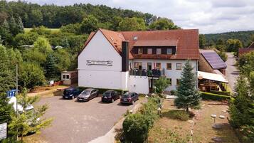 A building with a sloped roof, a sign reading 'La Maison de la Nature,' and a parking area with several cars.