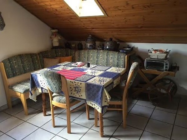 Ein Essbereich mit einem Holztisch, Stühlen, einer gesteppten Tischdecke und einem Vintage-Toaster.
