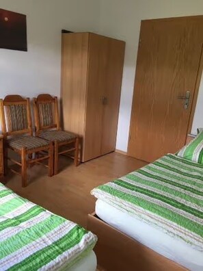 Ein Schlafzimmer mit zwei Einzelbetten, einem Holzschrank und einem Stuhl.