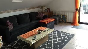 A living room with a sofa, a coffee table, a radiator, and a window with curtains.