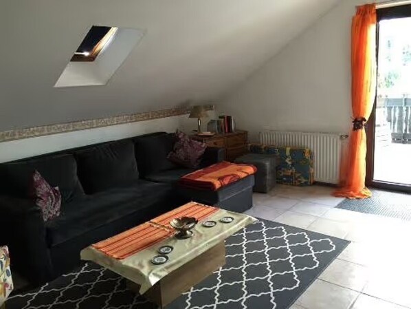 Un salon avec un canapé, une table basse, un radiateur et une fenêtre avec des rideaux.