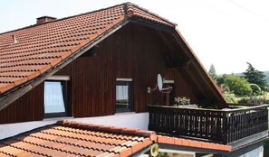 Un bâtiment en bois doté d’un toit en pente, d’un balcon avec une balustrade et d’une antenne parabolique.