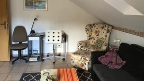 A room with a desk, chair, sofa, and a painting on the wall.