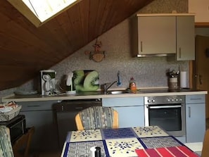Une cuisine équipée d’une table à manger, d’un four à micro-ondes, d’un évier et de placards.