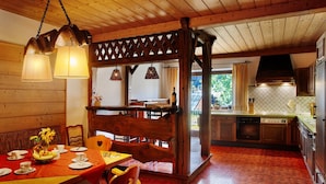 A wooden interior with a dining area, kitchen, and a view through a lattice window.