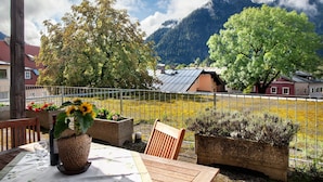 A table with a potted sunflower, a wine bottle, and a chair.