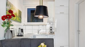Una cocina moderna con armarios blancos, una mesa de comedor con un jarrón de flores y una lámpara colgante negra.