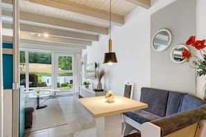 A modern living room with a sofa, a table, and a hanging light fixture.