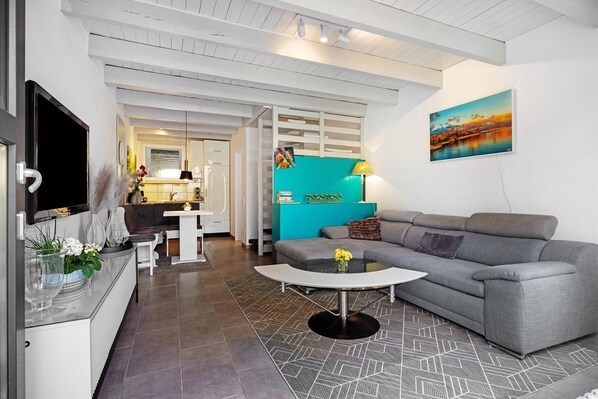 A modern living room with a grey sofa, a coffee table, and a TV.