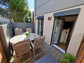 En terrasse med et rundt bord, fire stole og en lille plantepotte.
