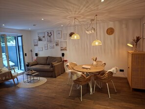 Ein modernes Wohnzimmer mit einem runden Esstisch, Korbstühlen, einer Couch und einer einzigartigen Deckenkonstruktion.