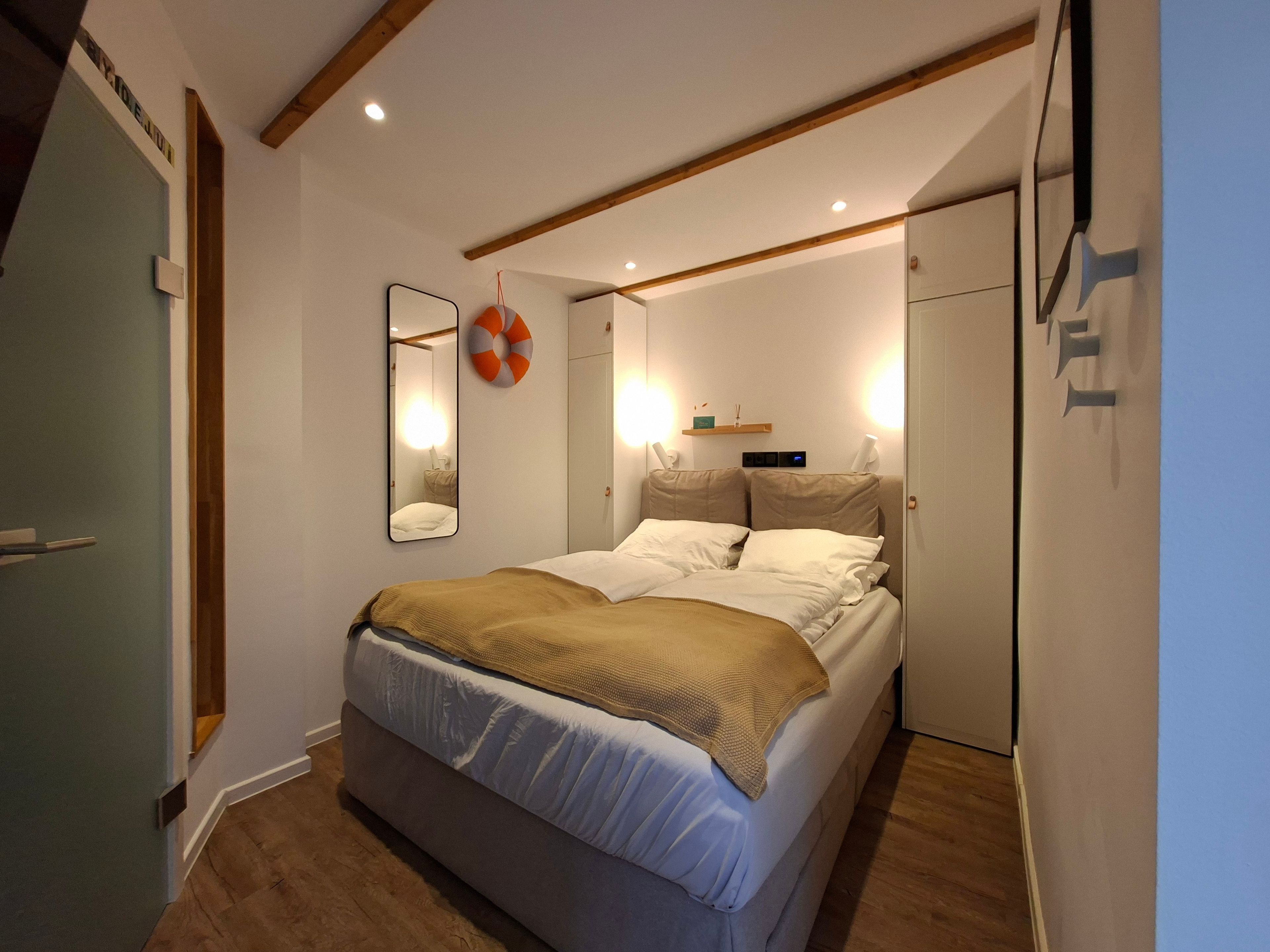 Ein Schlafzimmer mit einem Bett, Nachttischen, einem Spiegel und einem Wandregal.
