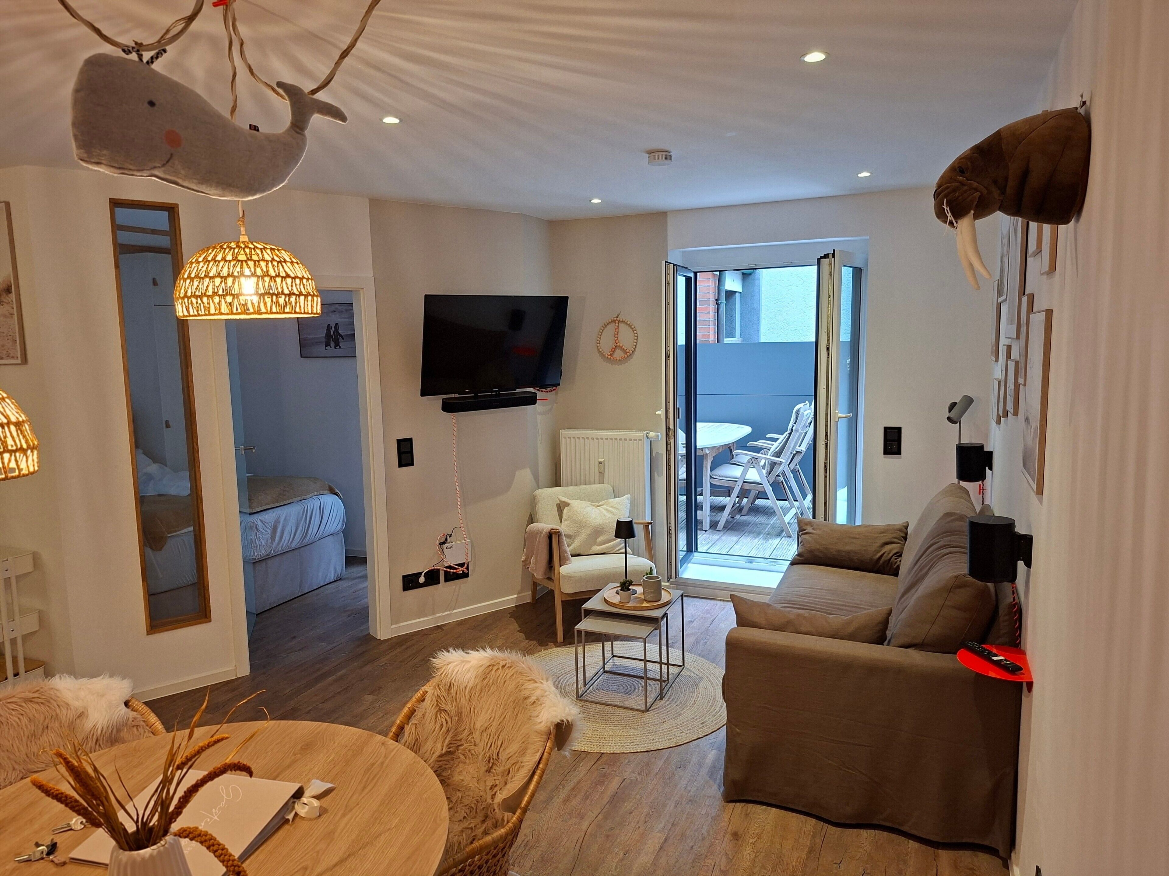 A modern living room with a television, sofa, and dining area.