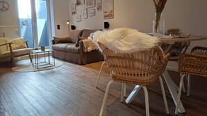 Ein Wohnzimmer mit einer Couch, Sesseln, einem Couchtisch und einem Esstisch.