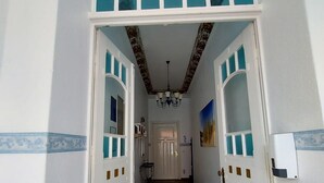 Ein Flur mit zwei Türen, einer Chandelüster und einem Gemälde an der Wand.