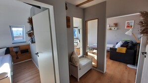 Ein modernes Interieur mit Holzboden, einem weißen Sofa, einem Essbereich und Blick durch eine Tür.