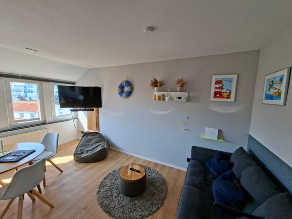 A living room with a sofa, a television, a coffee table, a bean bag, and a small rug.