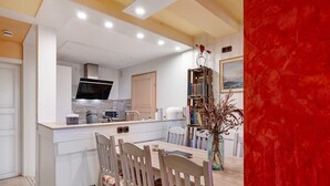 A modern kitchen with white cabinetry, a built-in microwave, and a dining area with a wooden table and chairs.