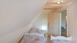 Une chambre avec deux lits simples, une table de chevet, une porte et un miroir.