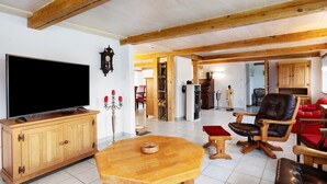 Una sala de estar con televisión, muebles de madera y un sofá rojo.