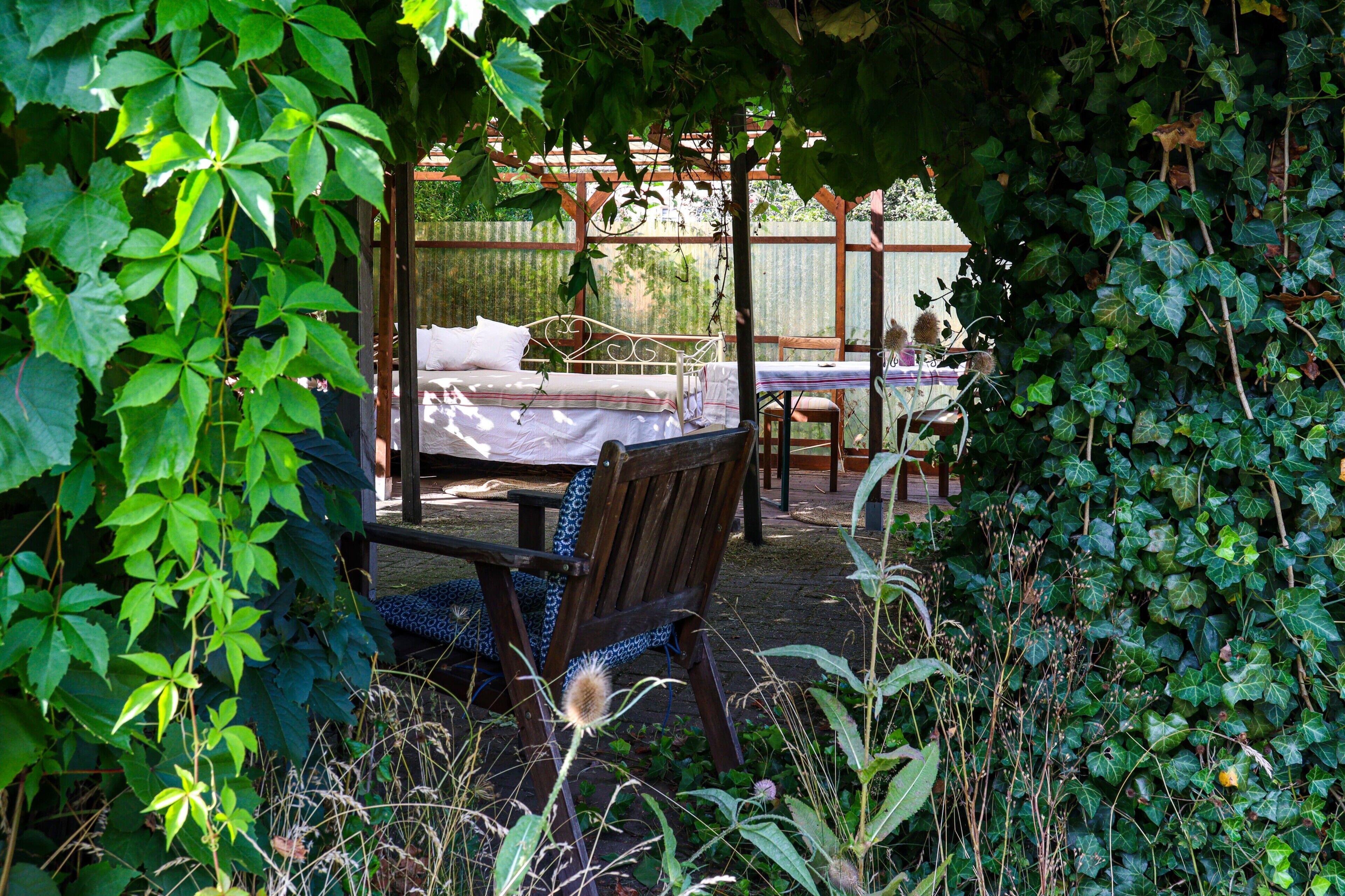 Een tuinpatio met een bed, een tafel en stoelen.