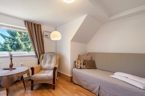 Une pièce comprenant un canapé, un fauteuil, une table, une lampe et une fenêtre avec des rideaux.