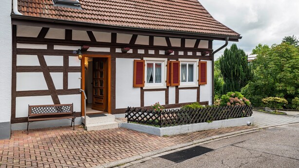 A traditional half-timbered house with a sloped roof, a wooden bench outside, and a small garden area. - Apartment 'Ferienhaus Albert' with Private Terrace and Wi-Fi (Bühl)
