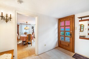 Ein Zimmer mit Holztür, einem Essbereich mit Tisch und Stühlen sowie einer Chandelüster.