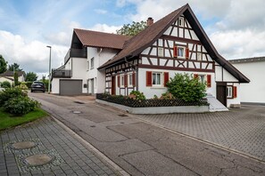 Une maison traditionnelle à colombages, avec un toit en pente, un garage et une allée pavée.