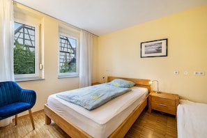 Una camera da letto con un letto, un comodino, una sedia e una finestra con tende.