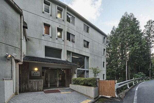 A modern building with a flat roof, multiple windows, and a small garden area with a wooden fence. - Sansuikan Kawayu Matsuya (Tanabe)