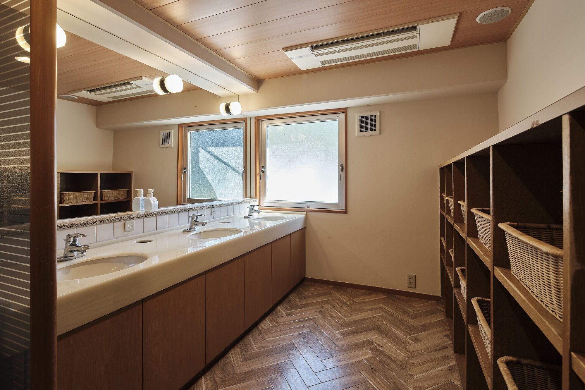 A modern bathroom with two sinks, a large window, and built-in wicker shelves.