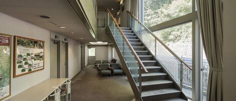 A spacious interior with a staircase leading to an upper level, a seating area with chairs, and a map on the wall.