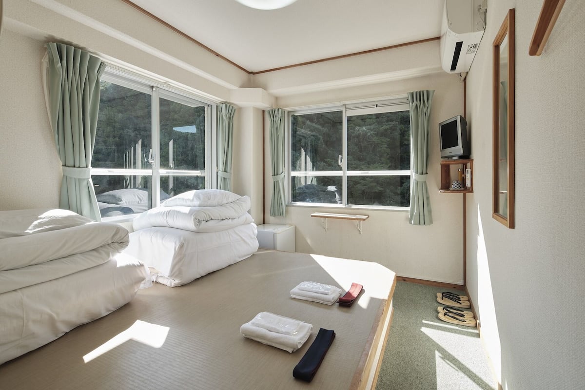 A hotel room with two beds, a TV, and a window with curtains.