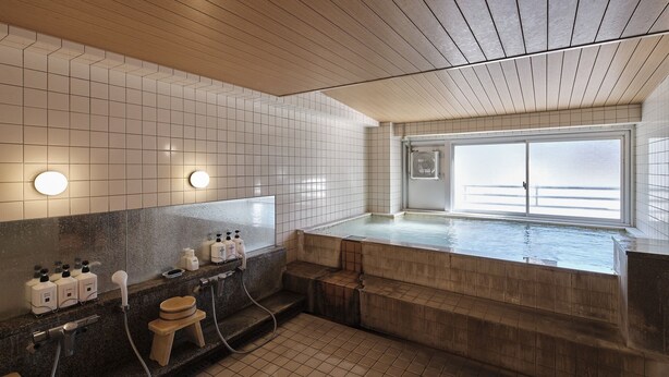 Un baño moderno con una bañera grande, techo de madera y paredes con azulejos.
