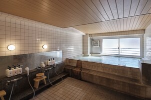 Un baño moderno con una bañera grande, techo de madera y paredes con azulejos.