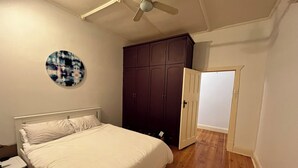 Ein Schlafzimmer mit Bett, Kleiderschrank, Deckenventilator und Tür.