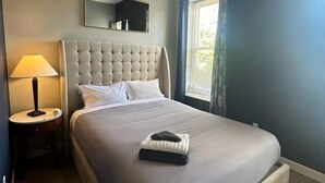 A neatly made bed with a headboard, a bedside lamp, and a ceiling fan. - Spacious 2BR unit near BJ Hospital (St. Louis)