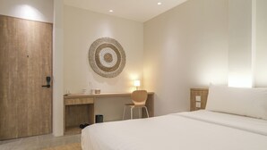 Ein Hotelzimmer mit einem Bett, einem Schreibtisch, einem Stuhl und einer Wandlampe.