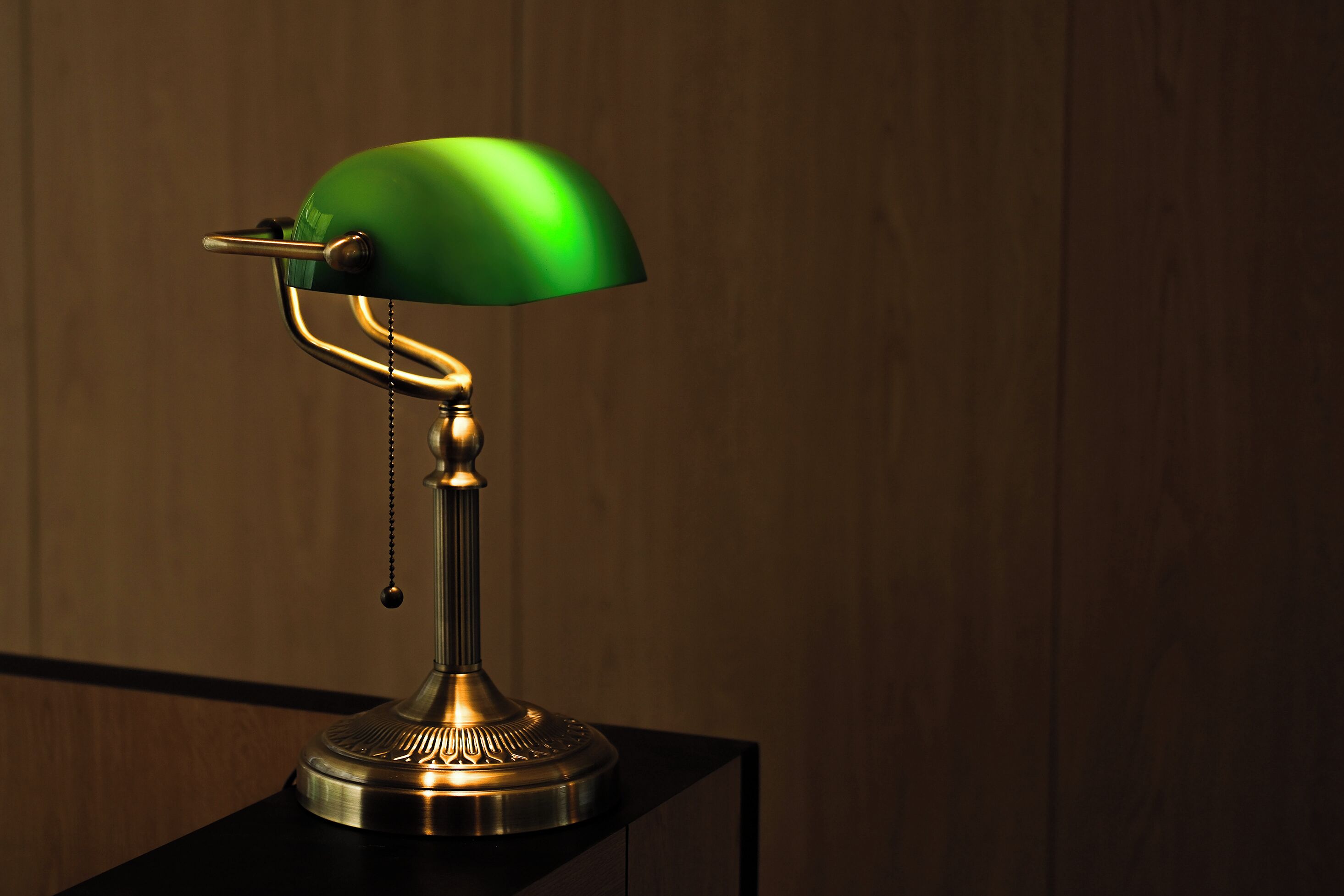 Une lampe de bureau avec un abat-jour vert et un pied en laiton.